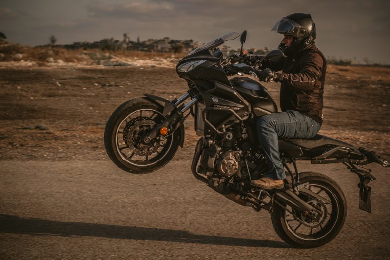 Biker mit Motorradjacke macht Wheelie