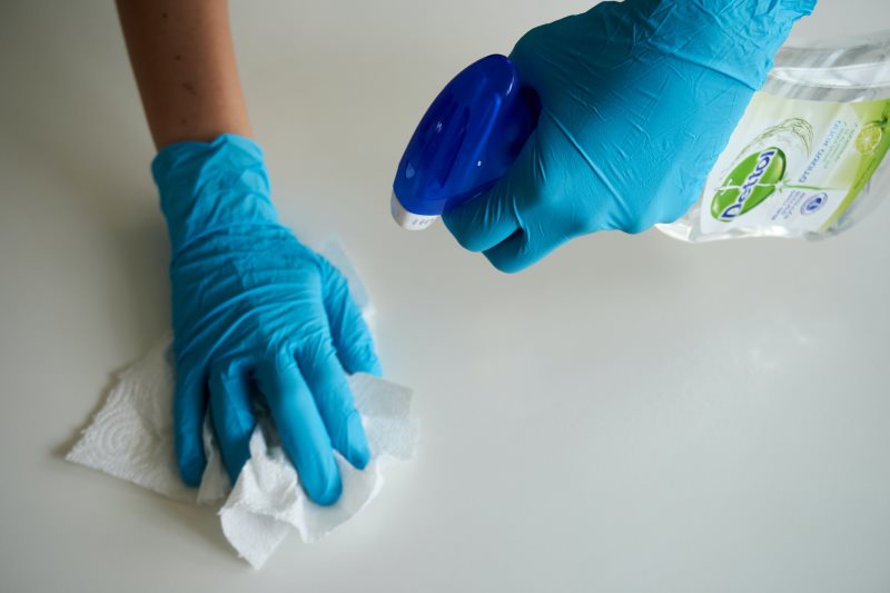 Frau putzt mit Handschuhen