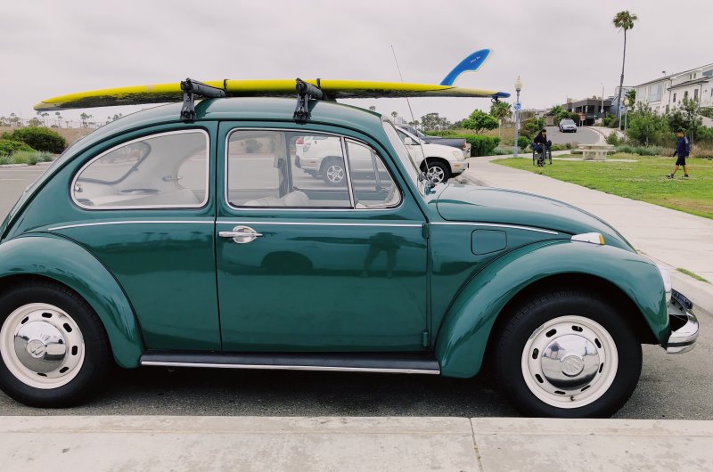 Auto auf Parkplatz mit Surfbrett auf Dachträger